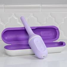 A white plastic device used for vaginal stretching in front of a white and purple case