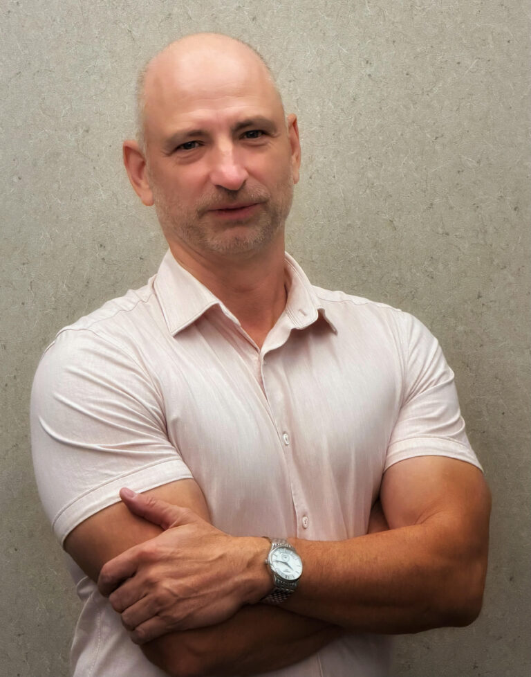 A bald man wearing a white golf shirt
